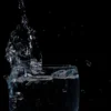 Gros plan d'eau éclaboussant dans un verre sur fond noir.