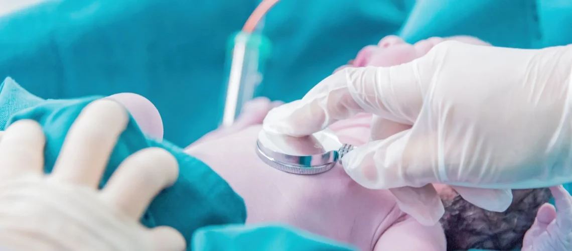 Professionnel de santé examinant un nouveau-né avec un stéthoscope dans un cadre hospitalier.