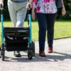 Couple âgé marchant ensemble avec un déambulateur par une journée ensoleillée dans un parc.