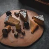 Plateau de fromages rustiques avec noix et raisins sur une planche en bois