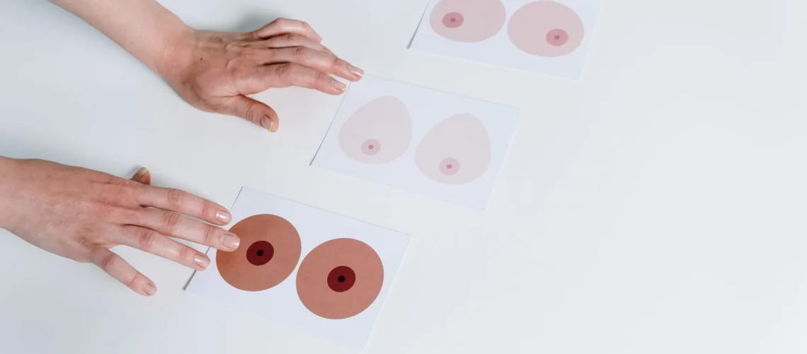 Des mains disposent des illustrations anatomiques du sein pour la sensibilisation et l'éducation sur une surface blanche.