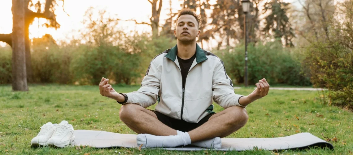 Homme méditant en plein air dans un parc tranquille au coucher du soleil, favorisant la relaxation et la pleine conscience