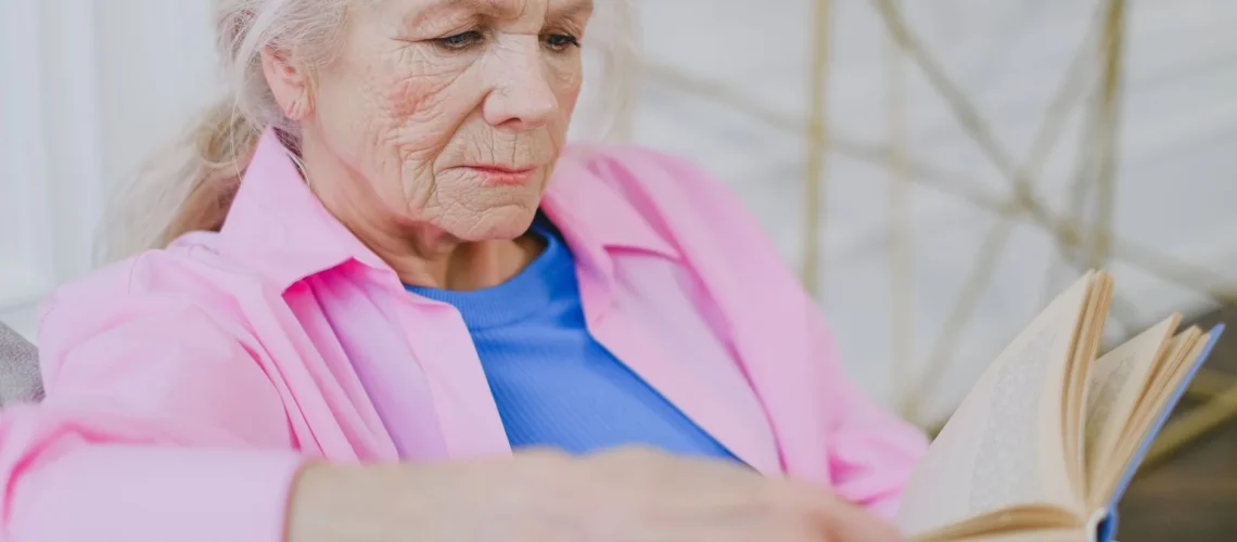 Une femme âgée se détend à l'intérieur, savourant un moment de calme avec un livre.