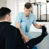 Un kinésithérapeute aidant un patient à faire des exercices de jambe lors d'une séance de rééducation en clinique