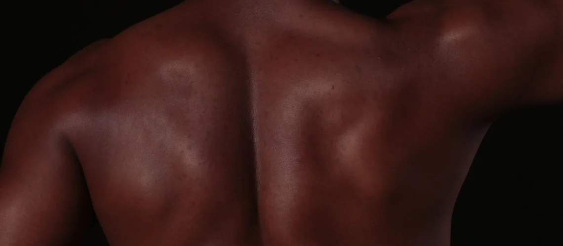 Gros plan du dos d'un homme musclé, montrant une peau et des muscles définis en studio.