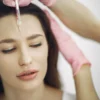 Gros plan sur un soin du visage avec injection en institut de beauté, centré sur le front.