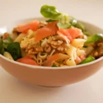 Salade de pâtes au saumon fumé, noix et verdure fraîche dans un bol en céramique.