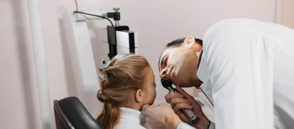Un médecin examine l'oreille d'une jeune fille lors d'une consultation en clinique.