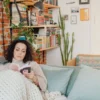 Femme se détendant avec un livre sur un canapé confortable dans une bibliothèque à domicile.