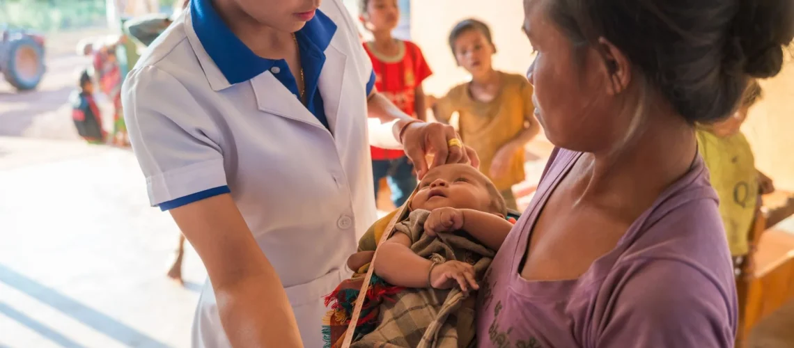 Professionnel de santé aidant une mère avec son nourrisson dans une clinique rurale au Laos.