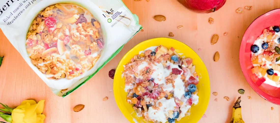 Bols colorés de muesli crémeux et de fruits frais sur une table en bois, parfaits pour un petit-déjeuner sain.