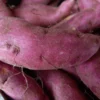 Image rapprochée de patates douces violettes fraîches, montrant leur texture et leur couleur en détail.