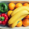 Mélange vibrant de fruits et légumes, dont bananes et poivrons, dans un bol.