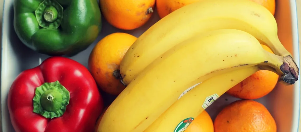 Mélange vibrant de fruits et légumes, dont bananes et poivrons, dans un bol.