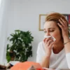 Femme adulte se mouchant à l'intérieur, ne se sentant pas bien
