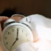 Gros plan d'une main tendant vers un réveil qui sonne, symbolisant le réveil matinal.