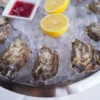 Plateau de fruits de mer gastronomique avec huîtres fraîches servies sur glace, citron et sauce.