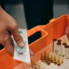 Gros plan de mains organisant des flacons et une seringue dans une trousse de premiers secours, soulignant l'état de préparation aux urgences.