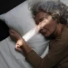 Une femme âgée dort paisiblement dans un lit sous une lumière douce