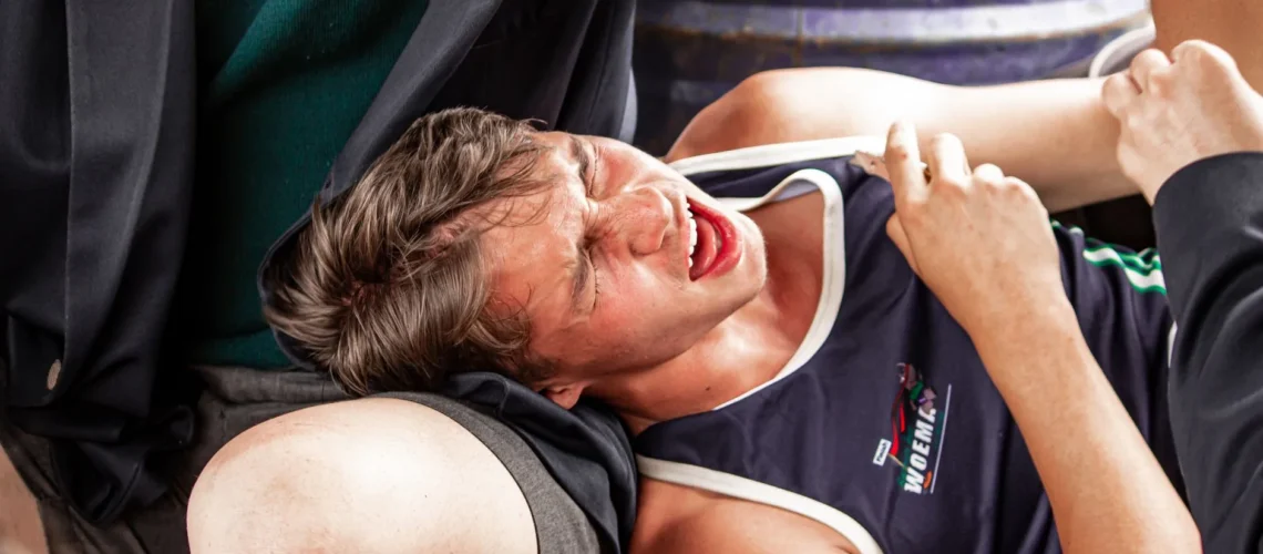 Jeune athlète grimaçant de douleur à cause de crampes musculaires pendant une compétition sportive