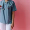 Un professionnel de santé tenant un ruban rose pour la sensibilisation au cancer du sein sur fond rose.