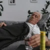 Homme âgé allongé sur un canapé avec des médicaments, se sentant mal et se reposant à l'intérieur