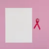 Fond rose avec papier vierge et ruban rouge symbolisant la sensibilisation au cancer du sein.