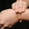 Gros plan sur les mains d'une personne pressant son poignet, mettant l'accent sur la peau et sa texture.