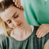 Masseur professionnel en tenue médicale verte réalisant un massage thérapeutique du cou sur une patiente détendue en tenue décontractée