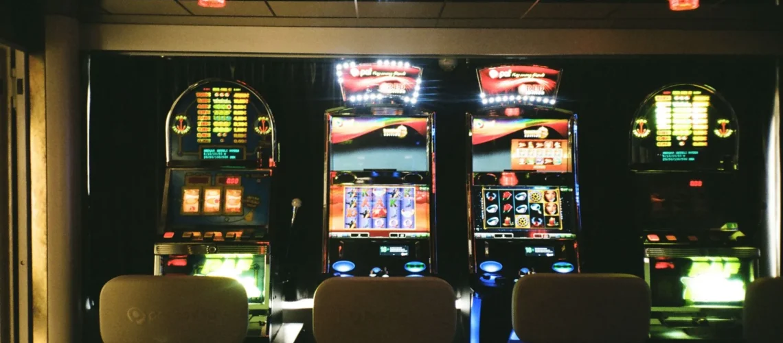 Machines à sous dans un casino faiblement éclairé avec plafond réfléchissant et chaises vides.