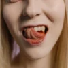 Portrait en gros plan d'une femme blonde tirant la langue sur fond neutre.