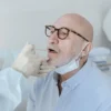 Homme âgé dans un cadre médical subissant un test de prélèvement pour un bilan de santé.